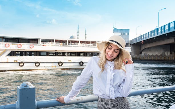 Bosphorus cruise ship near Galata Bridge, Istanbul, with a smiling woman in a hat.
