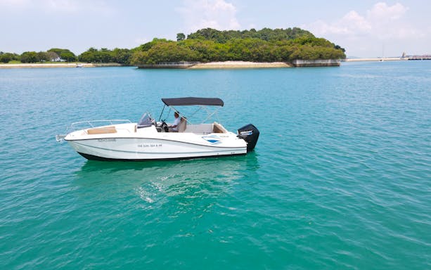 Boat cruising near lush island on Seafarer's Channel Tour with tropical drink.