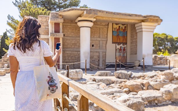 Woman using phone for audio tour at Knossos archaeological site, Crete.