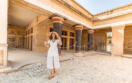 Visitor exploring Knossos Palace with audio tour on phone, Crete.