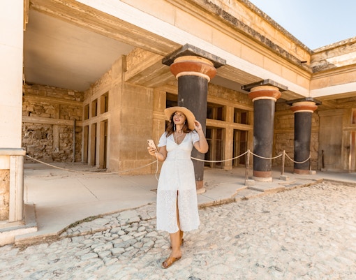 Visitor exploring Knossos Palace with audio tour on phone, Crete.