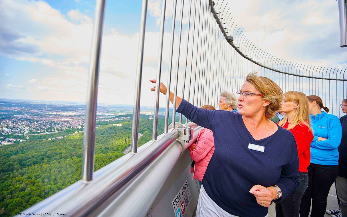 Visitors on the observation deck of Fernsehturm Stuttgart, overlooking the cityscape.