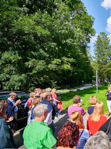 Group tour at the base of Fernsehturm Stuttgart, guide speaking to visitors.