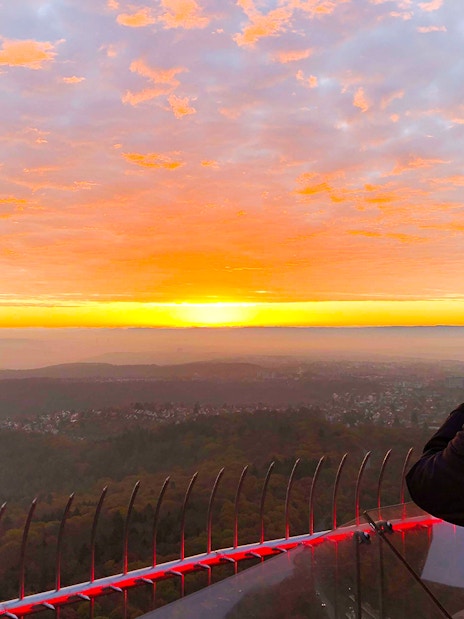 Person photographing sunset from Fernsehturm Stuttgart observation deck.
