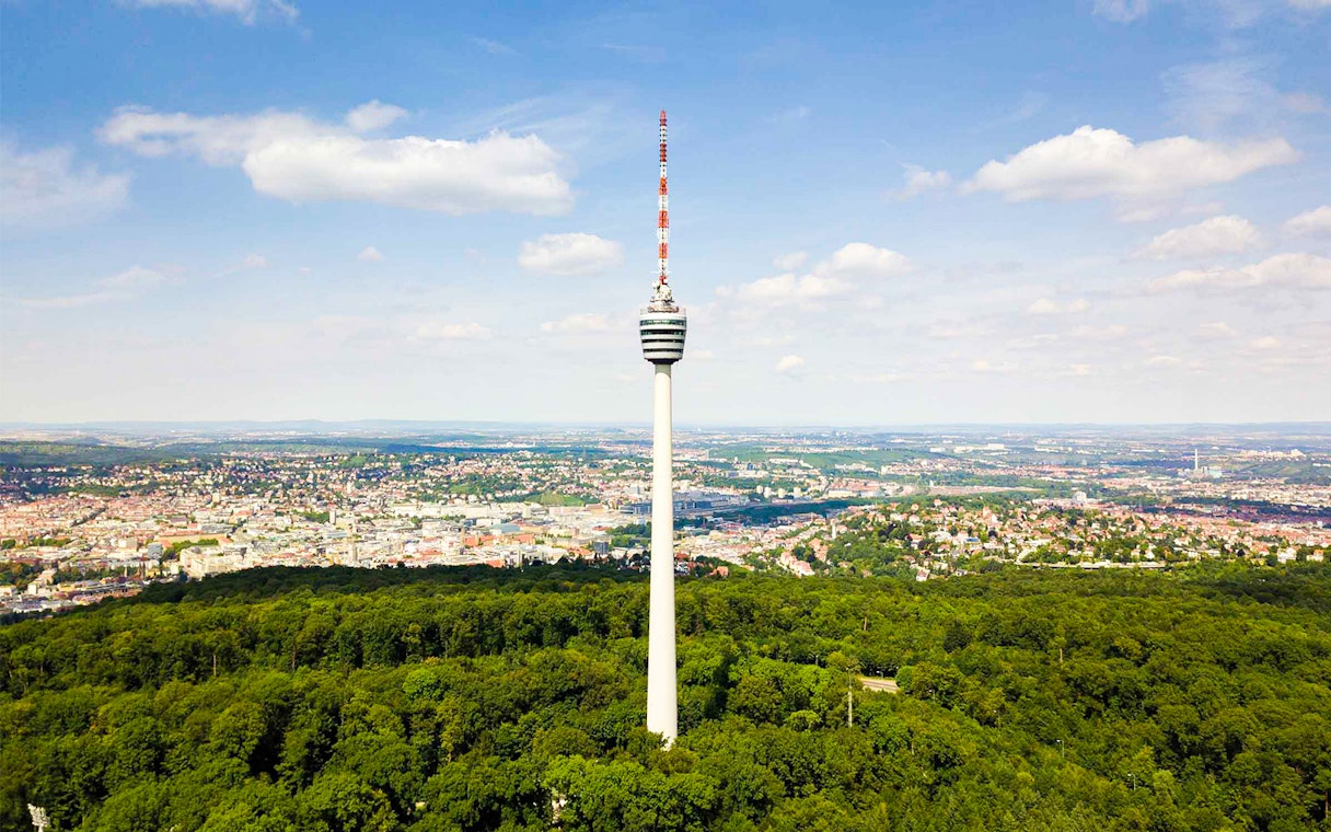 Fernsehturm Stuttgart tower overlooking cityscape and forest.