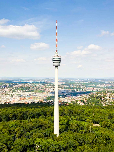 Fernsehturm Stuttgart tower overlooking cityscape and forest.