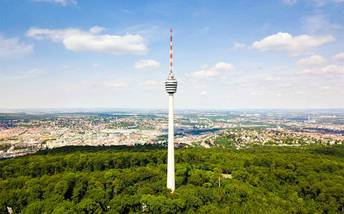Fernsehturm Stuttgart tower overlooking cityscape and forest.