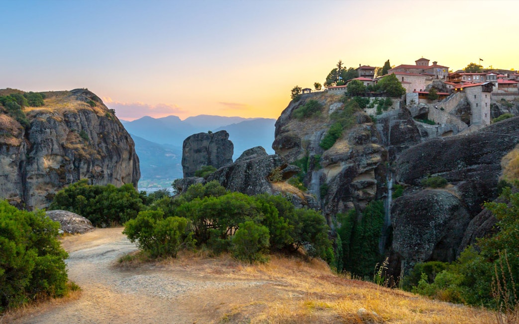 Meteora rock formations and monastery at sunset, Greece, on Hidden Trails Hiking Tour.