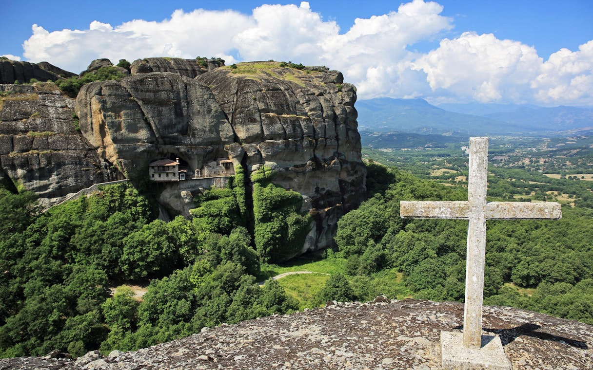Meteora rock formations with monastery and cross, Greece, on Hidden Trails Hiking Tour.