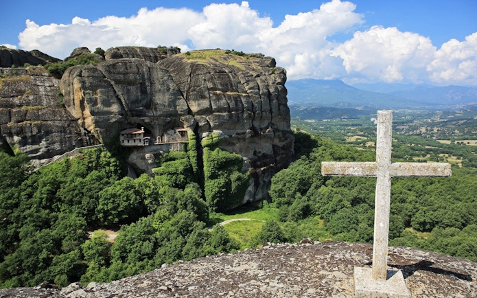 Meteora rock formations with monastery and cross, Greece, on Hidden Trails Hiking Tour.