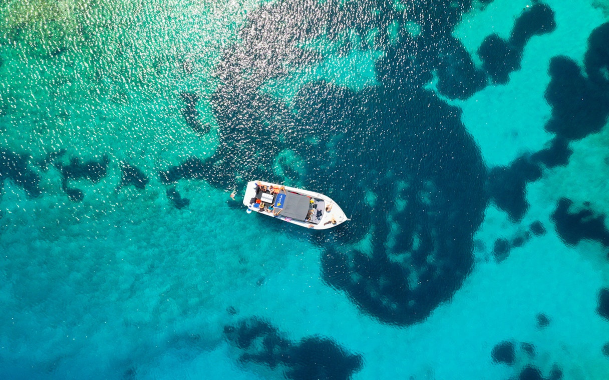 Aerial view of a boat on clear blue waters during a tour from Split to Blue Cave, Vis, and Hvar.