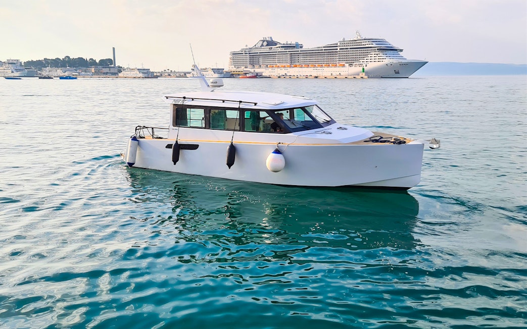 Boat on Adriatic Sea near Split with cruise ship in background.