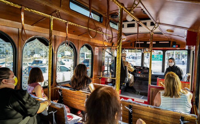 Inside view of a cultural city tour bus with passengers and a masked guide.