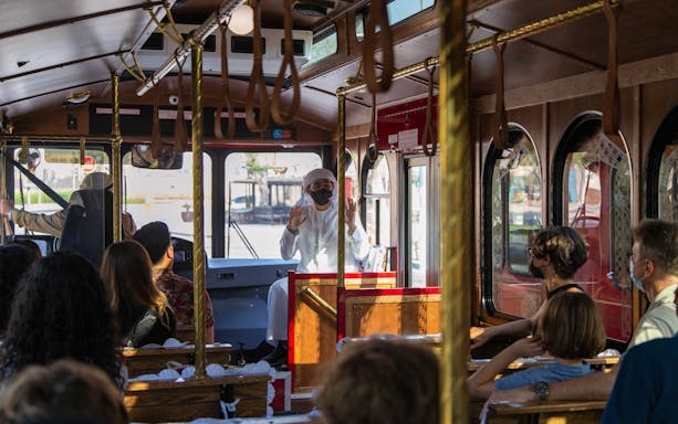 Tour guide speaking to passengers on a cultural tram tour, "Culture on Wheels.
