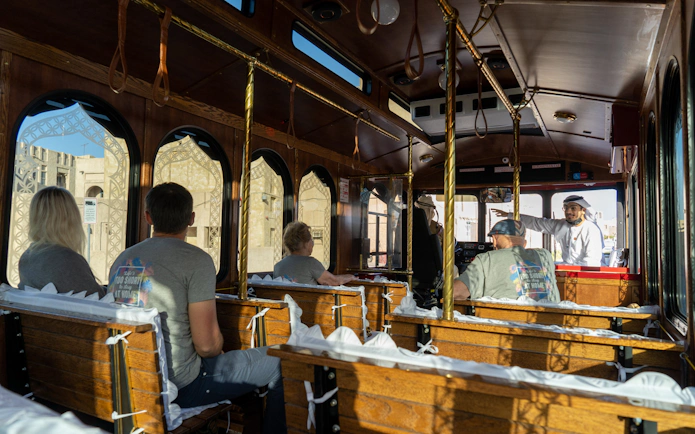 Inside view of a cultural trolley tour with passengers and a guide in traditional attire.