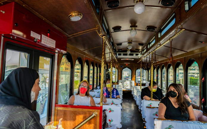 Tourists wearing masks seated inside a cultural tram tour, "Culture on Wheels.