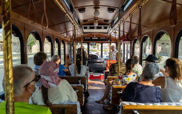 Tourists seated inside a traditional Emirati trolley bus during a hospitality dining experience.