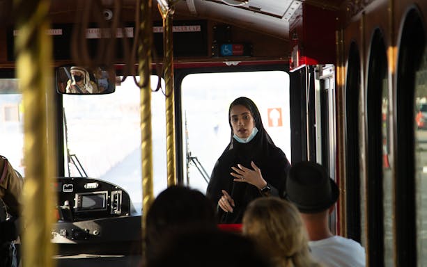 Tour guide explaining Emirati hospitality on a bus during a dining experience.