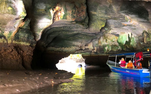 Cruise boat navigating through a cave in Langkawi UNESCO Geopark Mangrove.