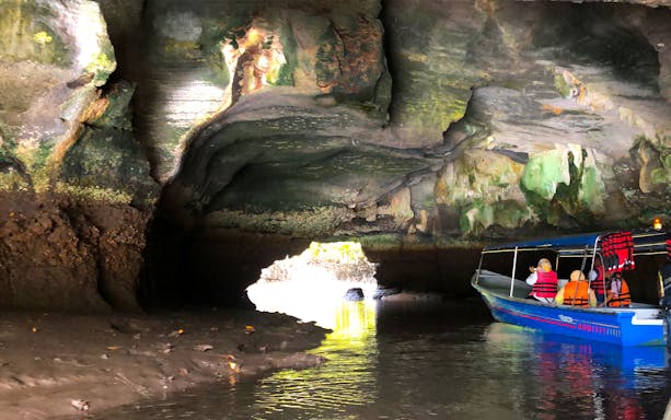 Cruise boat navigating through a cave in Langkawi UNESCO Geopark Mangrove.