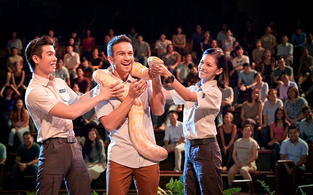 Guests interacting with a snake at Singapore Night Safari show.