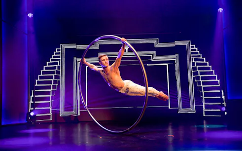 Performer in a Cyr wheel during Flying Dreams show with geometric stage design.