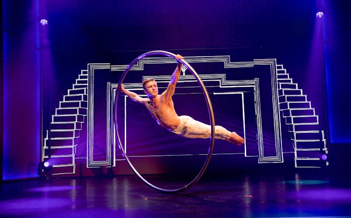 Performer in a Cyr wheel during Flying Dreams show with geometric stage design.