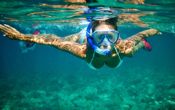 Snorkeler exploring underwater near Isole Ciclopi, Catania.