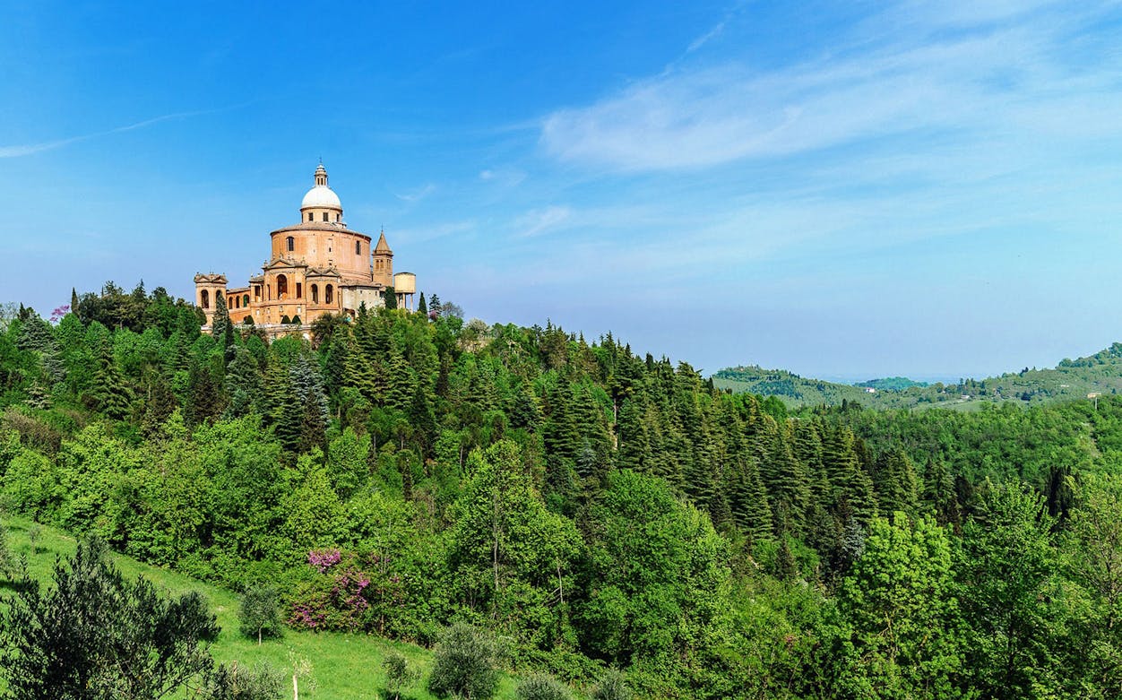 Sanctuary of the Madonna di San Luca on a hill surrounded by trees in Bologna, Italy.