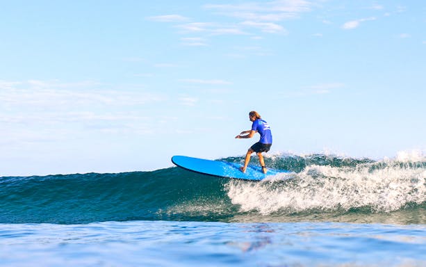 Surfer riding a wave during a lesson in Byron Bay, Australia.