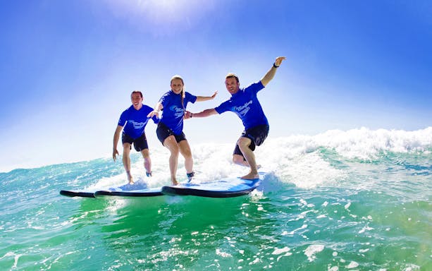 Surfing lesson with three people riding waves in Byron Bay.