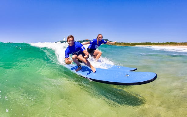 Surfers riding a wave during a lesson at Byron Bay, Australia.