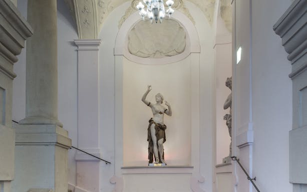 Statue in Theatre Museum interior with ornate ceiling and columns.