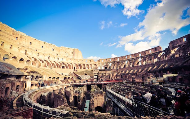 Colosseum interior with tourists exploring ancient ruins, Rome.