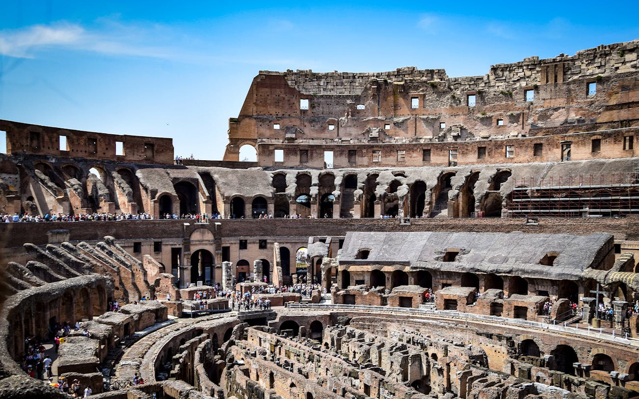 Colosseum interior with tourists exploring ancient Roman architecture in Rome, Italy.