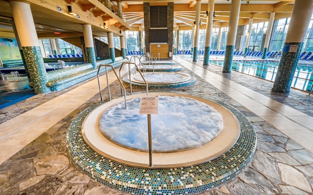 Jacuzzi area inside Chocholow Thermal Baths with tiled floors and large windows.