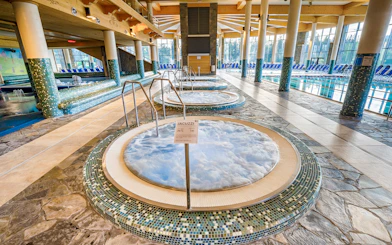 Jacuzzi area inside Chocholow Thermal Baths with tiled floors and large windows.