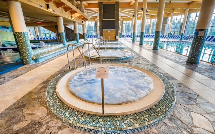 Jacuzzi area inside Chocholow Thermal Baths with tiled floors and large windows.