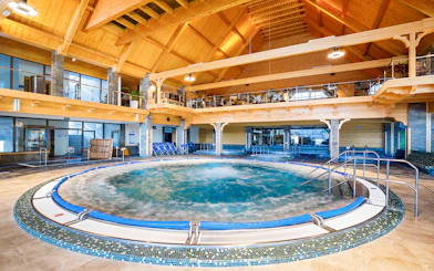 Indoor pool at Chocholow Thermal Baths with wooden ceiling and seating area.