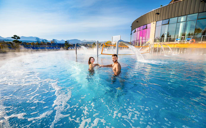 Couple enjoying Chocholow Thermal Baths with mountain view and hotel transfers.