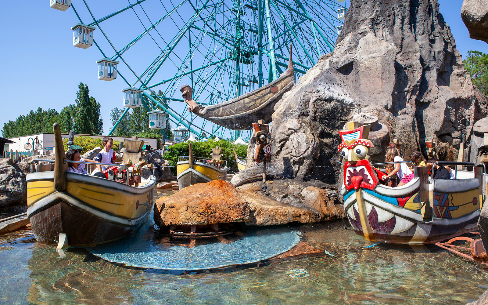 Boats on water ride at Mirabilandia with Ferris wheel in background.