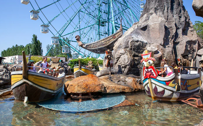 Boats on water ride at Mirabilandia with Ferris wheel in background.