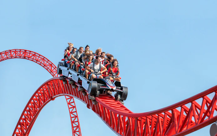 Roller coaster ride at Mirabilandia theme park, Italy, with passengers on a red track.