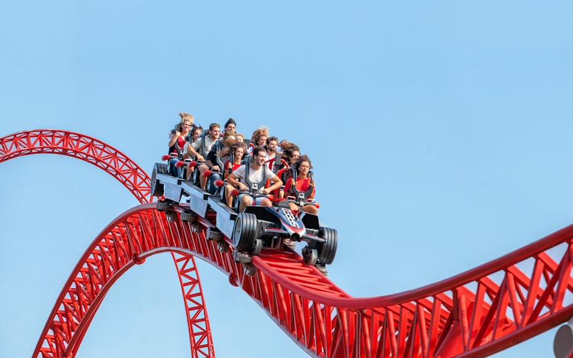 Roller coaster ride at Mirabilandia theme park, Italy, with passengers on a red track.
