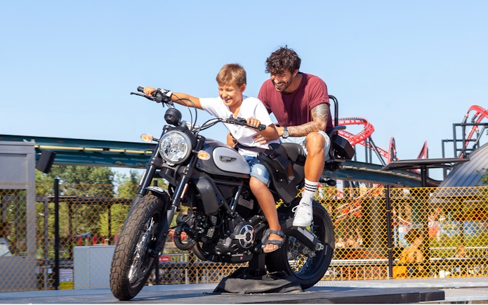Father and son on a motorcycle ride at Mirabilandia amusement park.