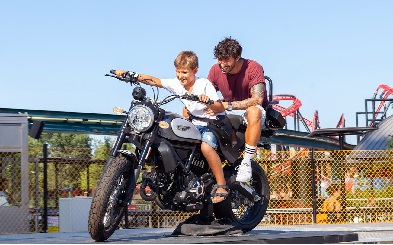 Father and son on a motorcycle ride at Mirabilandia amusement park.