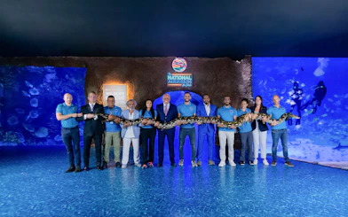 Group holding a large snake at National Aquarium Abu Dhabi.