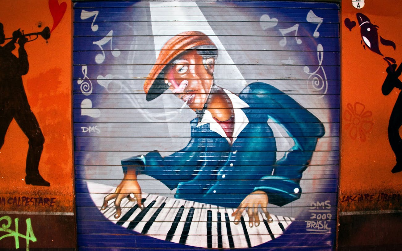 Street art of a musician playing piano with musical notes in Bologna.
