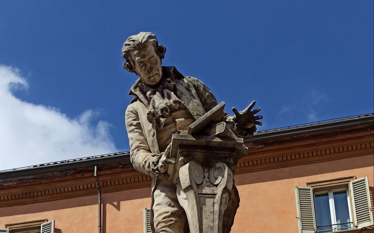 Statue of Luigi Galvani in Bologna against a clear blue sky.