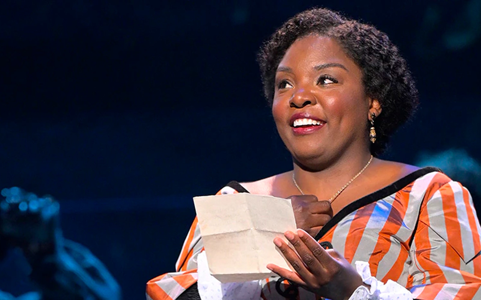 Performer holding a letter on stage during Paradise Square show.